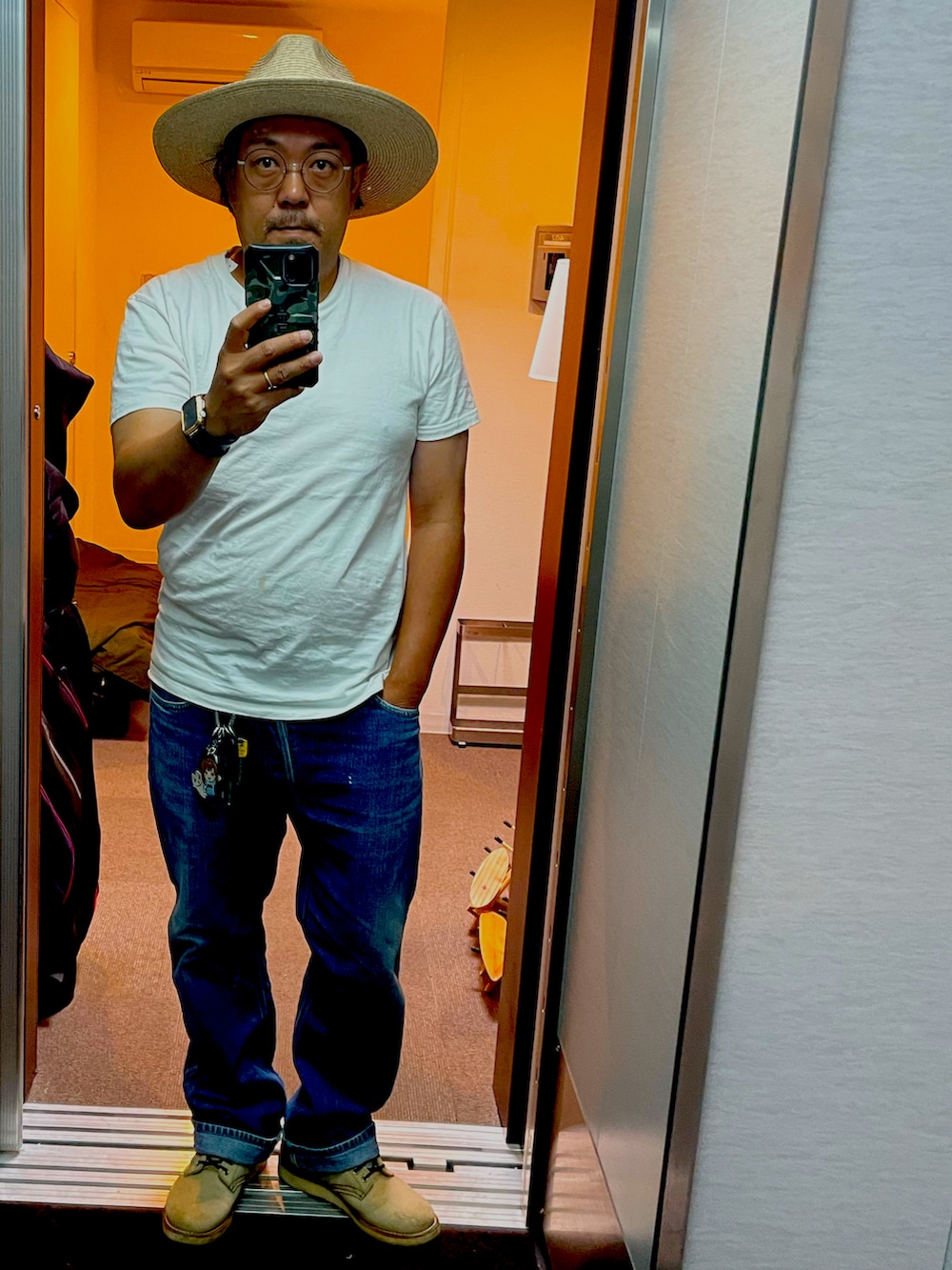 ホワイト系のTシャツ/カットソー、ベージュ系のブーツ、ブルー系のデニムパンツを着用したメンズの春コーディネートの2枚目の写真