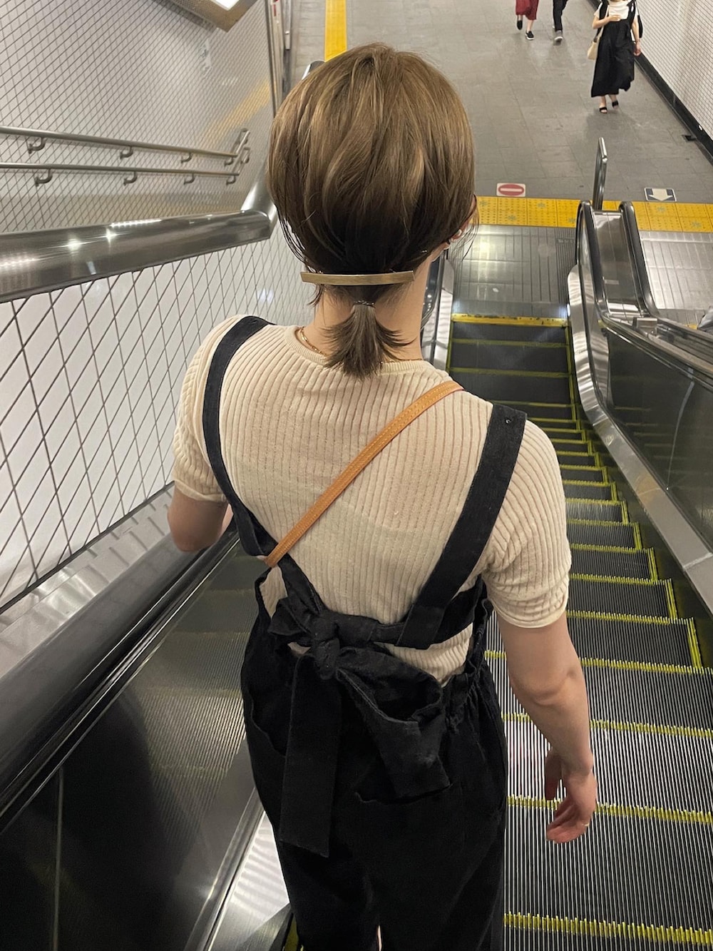 ベージュ系のTシャツ/カットソー、ブラック系のサロペット/オーバーオール、ブラウン系のサンダルを着用したレディースの夏コーディネートの2枚目の写真