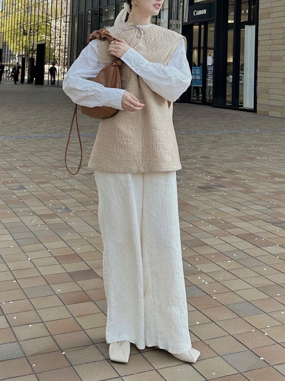 ホワイト系のパンツ、ベージュ系のベストを着用したレディースの春コーディネートの3枚目の写真