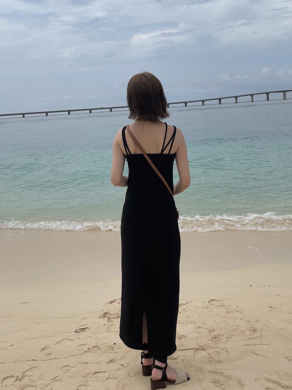 ブラック系のサンダル、ブラック系のワンピース、ブラウン系のショルダーバッグを着用したレディースの夏コーディネートの2枚目の写真