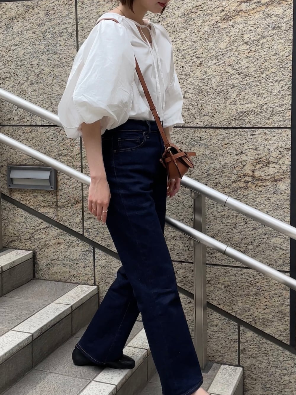 ブルー系のデニムパンツ、ホワイト系のシャツ/ブラウス、ブラウン系のショルダーバッグを着用したレディースの春コーディネートの2枚目の写真