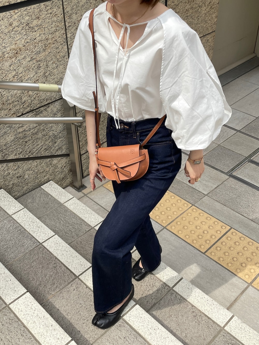 ブルー系のデニムパンツ、ホワイト系のシャツ/ブラウス、ブラウン系のショルダーバッグを着用したレディースの春コーディネートの3枚目の写真