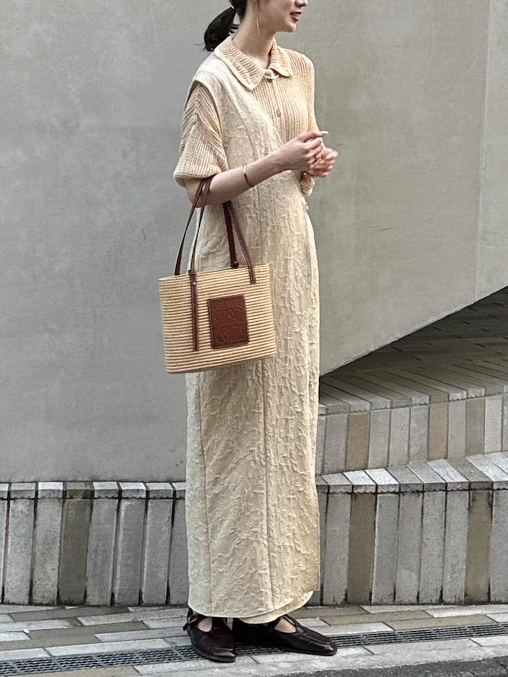 ベージュ系のバッグ、ベージュ系のジャンパースカート、ベージュ系のシャツ/ブラウスを着用したレディースの春コーディネートの2枚目の写真