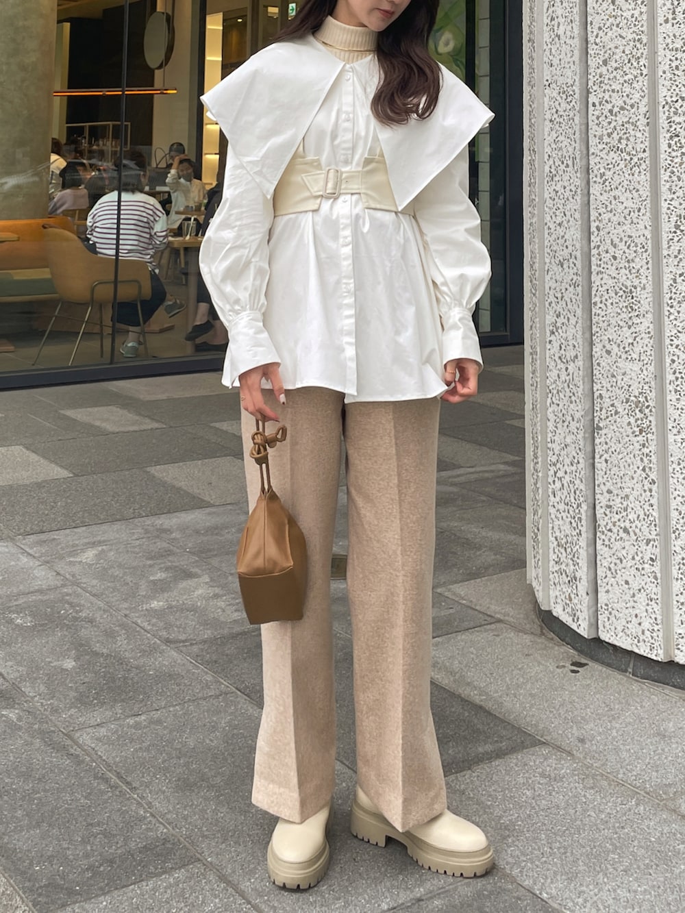 ベージュ系のスラックス、ベージュ系のブーツ、ブラウン系のバッグを着用したレディースの秋コーディネートの4枚目の写真