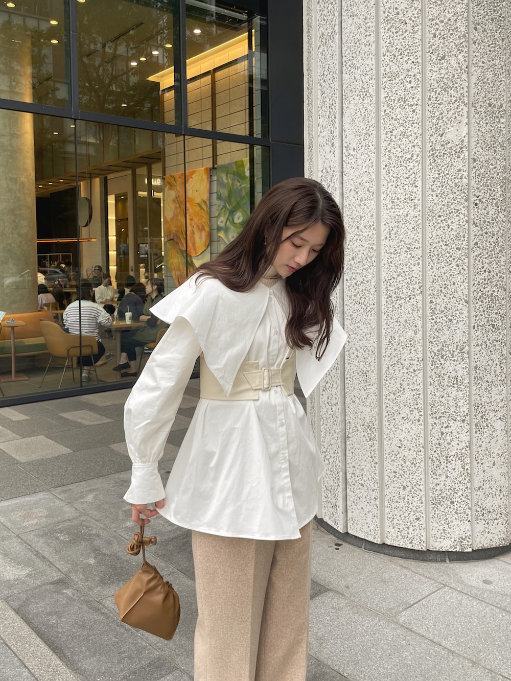 ベージュ系のスラックス、ベージュ系のブーツ、ブラウン系のバッグを着用したレディースの秋コーディネートの2枚目の写真