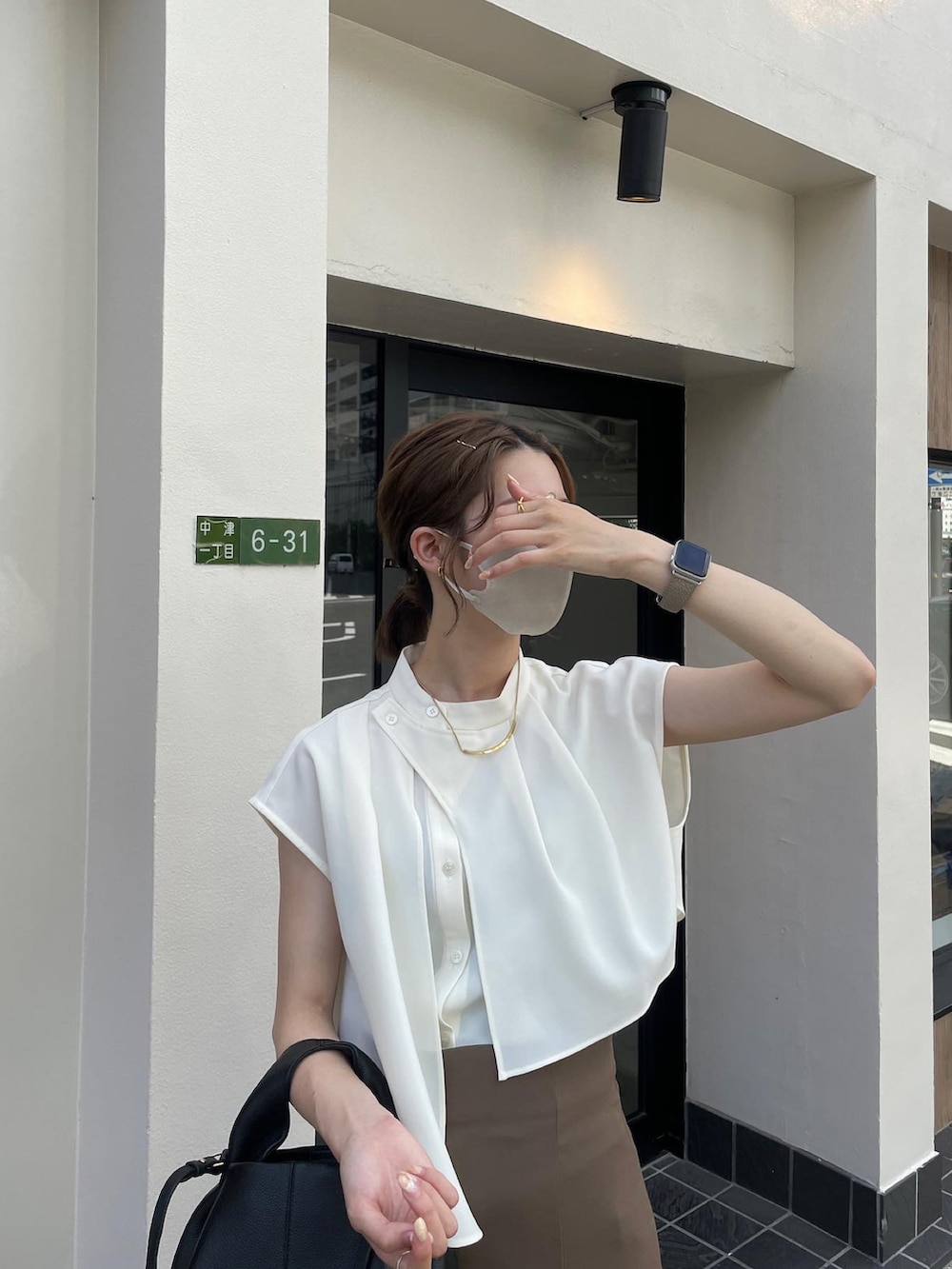 ホワイト系のシャツ/ブラウス、ベージュ系のスカート、ブラック系のサンダルを着用したレディースの夏コーディネートの2枚目の写真