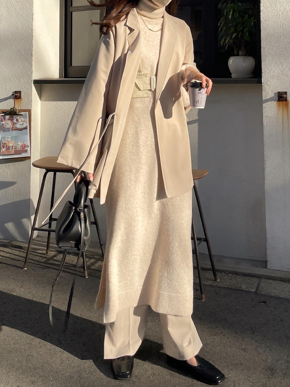 ベージュ系のスラックス、ホワイト系のワンピース、ベージュ系のテーラードジャケットを着用したレディースの秋コーディネートの2枚目の写真
