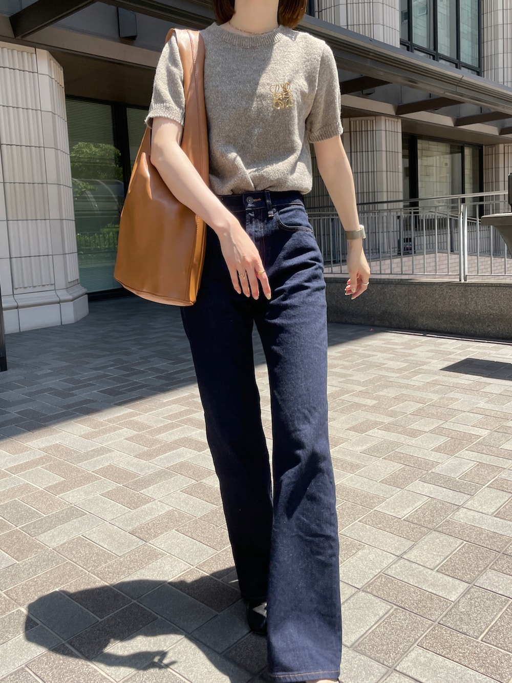 ブルー系のデニムパンツ、ブラック系のバレエシューズ、ブラウン系のトートバッグを着用したレディースの春コーディネートの3枚目の写真