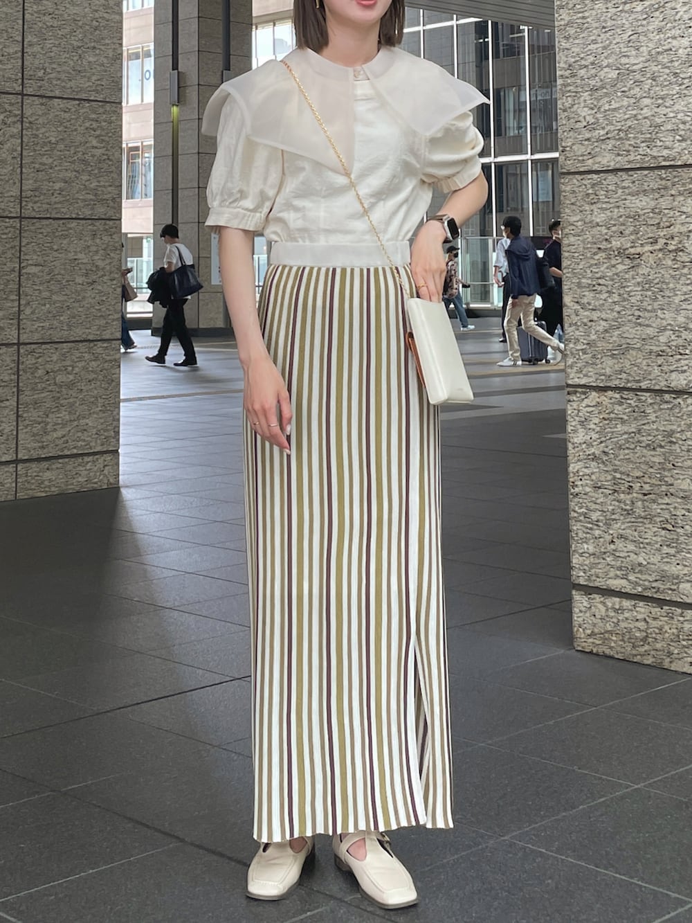グリーン系のスカート、ベージュ系のローファー、ホワイト系のシャツ/ブラウスを着用したレディースの夏コーディネートの2枚目の写真