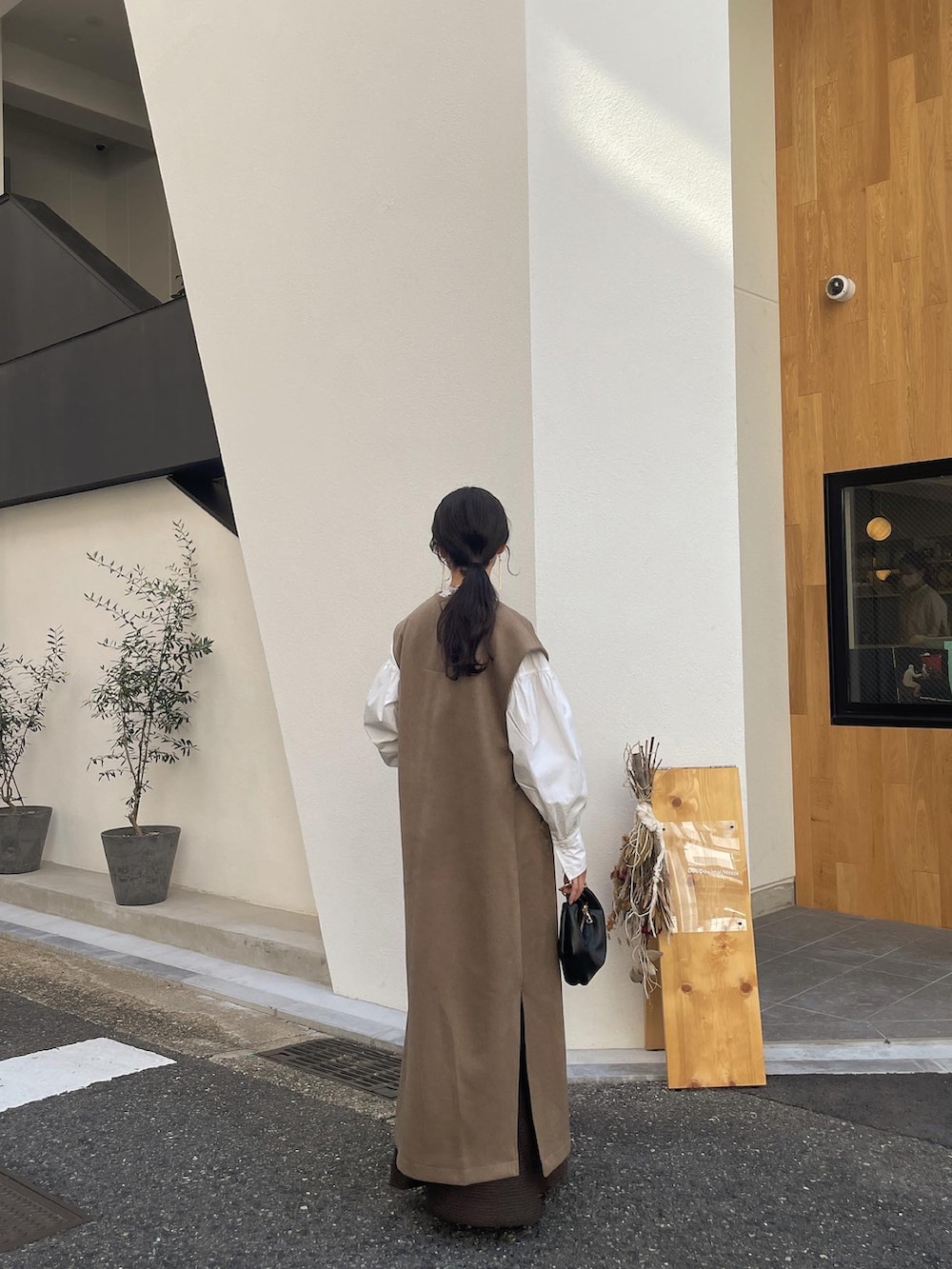 ベージュ系のローファー、ブラック系のショルダーバッグ、ブラウン系のスカートを着用したレディースの秋コーディネートの2枚目の写真