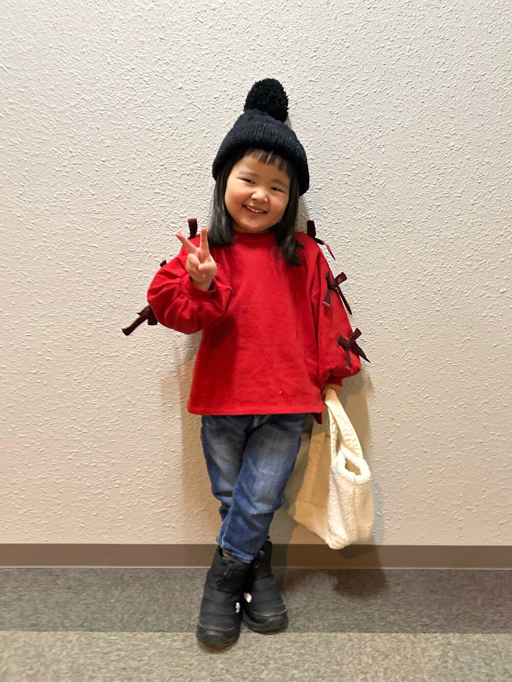 レッド系のスウェット、ブルー系のデニムパンツ、ブラック系のブーツを着用したキッズの冬コーディネートの2枚目の写真