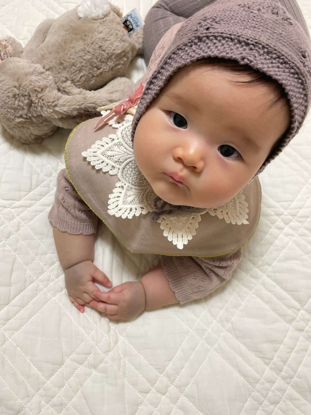 ピンク系のロンパース、ピンク系のスタイ/よだれかけ、ホワイト系のタイツ/ストッキングを着用したキッズの冬コーディネートの3枚目の写真