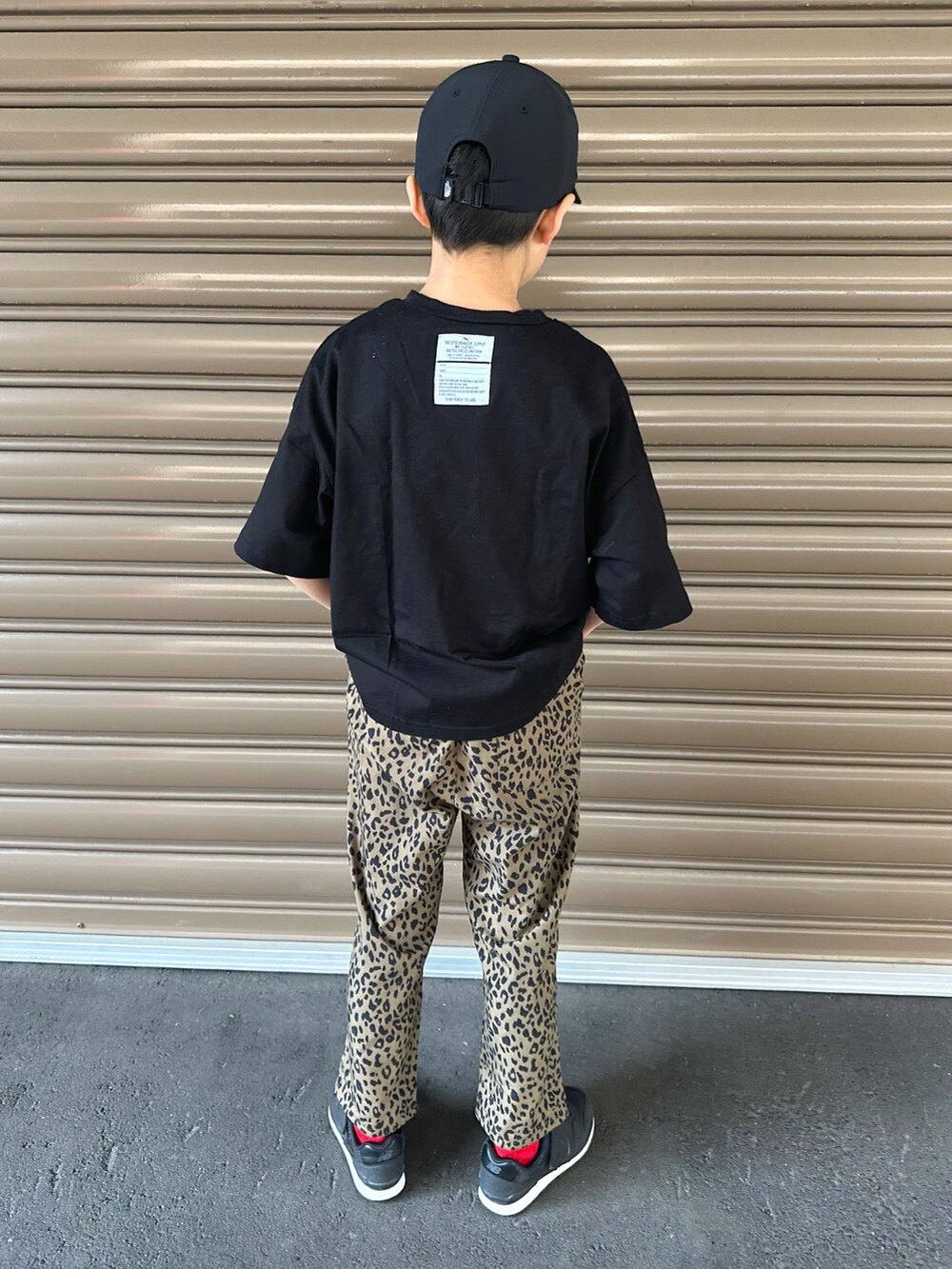 ブラック系のTシャツ/カットソー、ベージュ系のその他パンツ、ブラック系のスニーカーを着用したキッズの春コーディネートの3枚目の写真