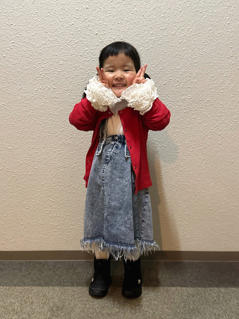 ホワイト系のTシャツ/カットソー、レッド系のカーディガン/ボレロ、ブルー系のスカートを着用したキッズの冬コーディネートの4枚目の写真