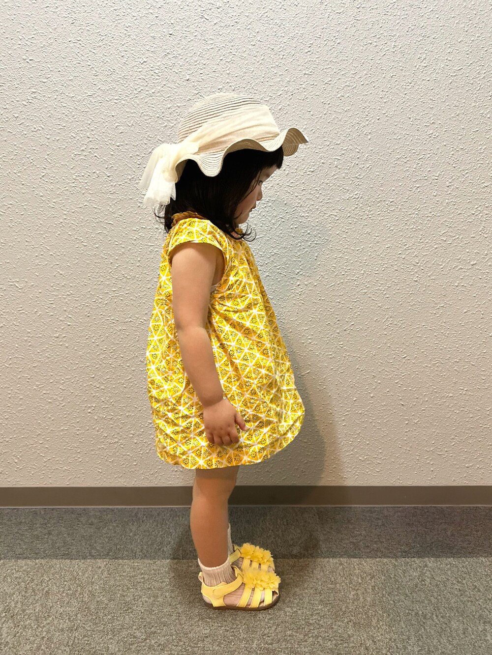 イエロー系のチュニック、ブルー系のデニムパンツ、イエロー系のサンダルを着用したキッズの夏コーディネートの2枚目の写真