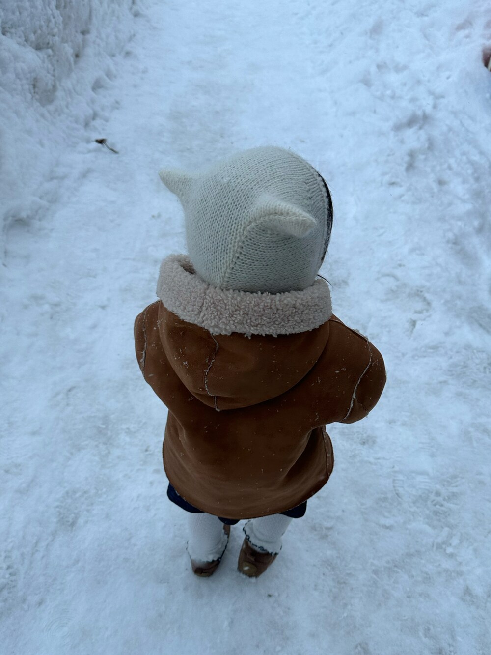 イエロー系のチュニック、ブラウン系のシューズ、ベージュ系のムートンコートを着用したキッズの冬コーディネートの5枚目の写真