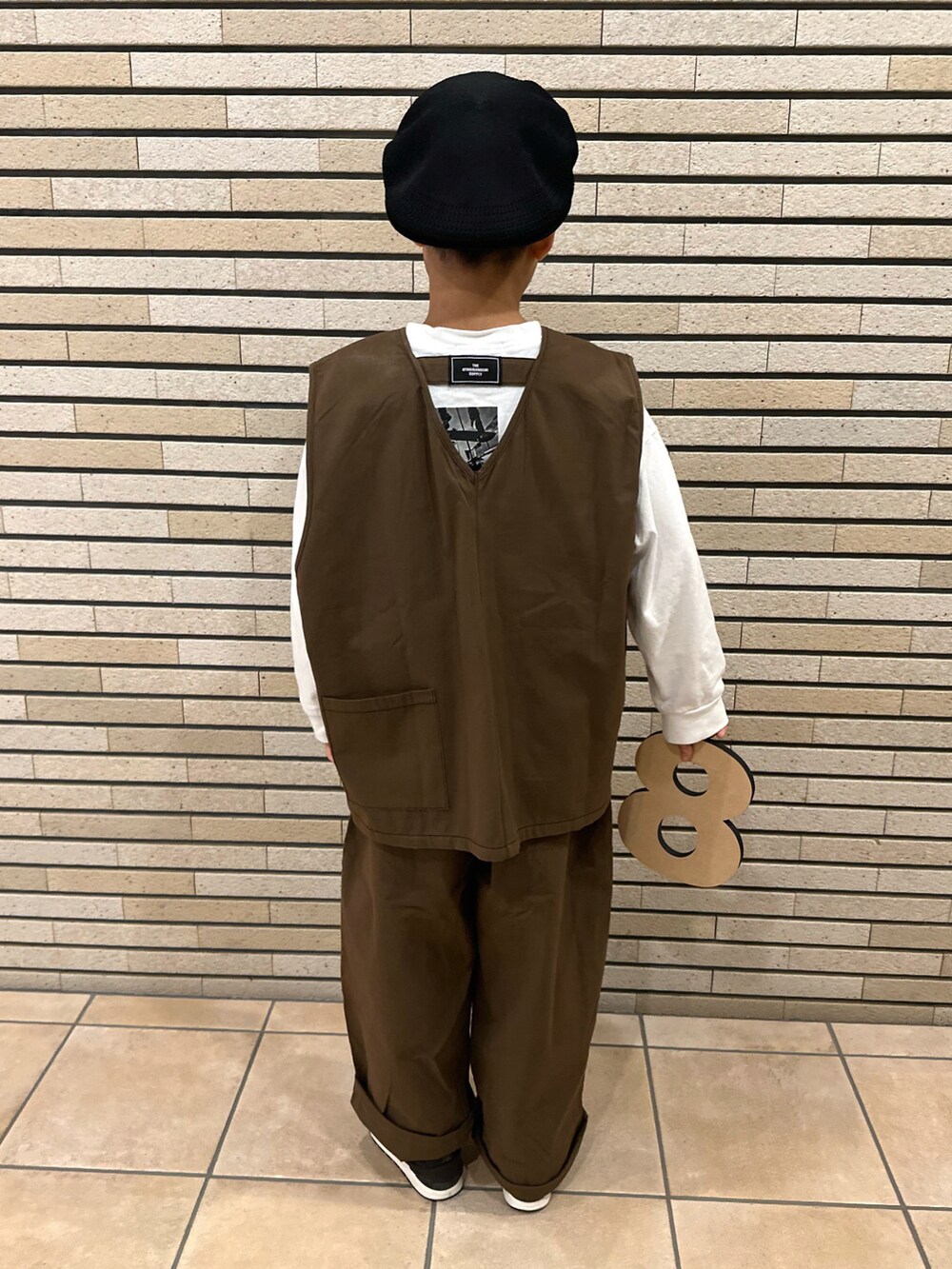 ブラウン系のベスト、ホワイト系のTシャツ/カットソー、ブラック系のスニーカーを着用したキッズの秋コーディネートの3枚目の写真