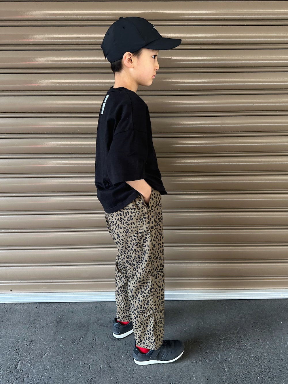 ブラック系のTシャツ/カットソー、ベージュ系のその他パンツ、ブラック系のスニーカーを着用したキッズの春コーディネートの2枚目の写真