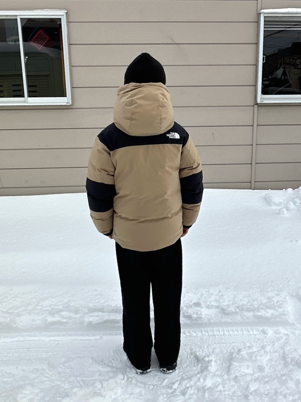 ブラック系のブーツ、ベージュ系のダウンジャケット/コート、ブラック系のスウェットパンツを着用したキッズの春コーディネートの3枚目の写真