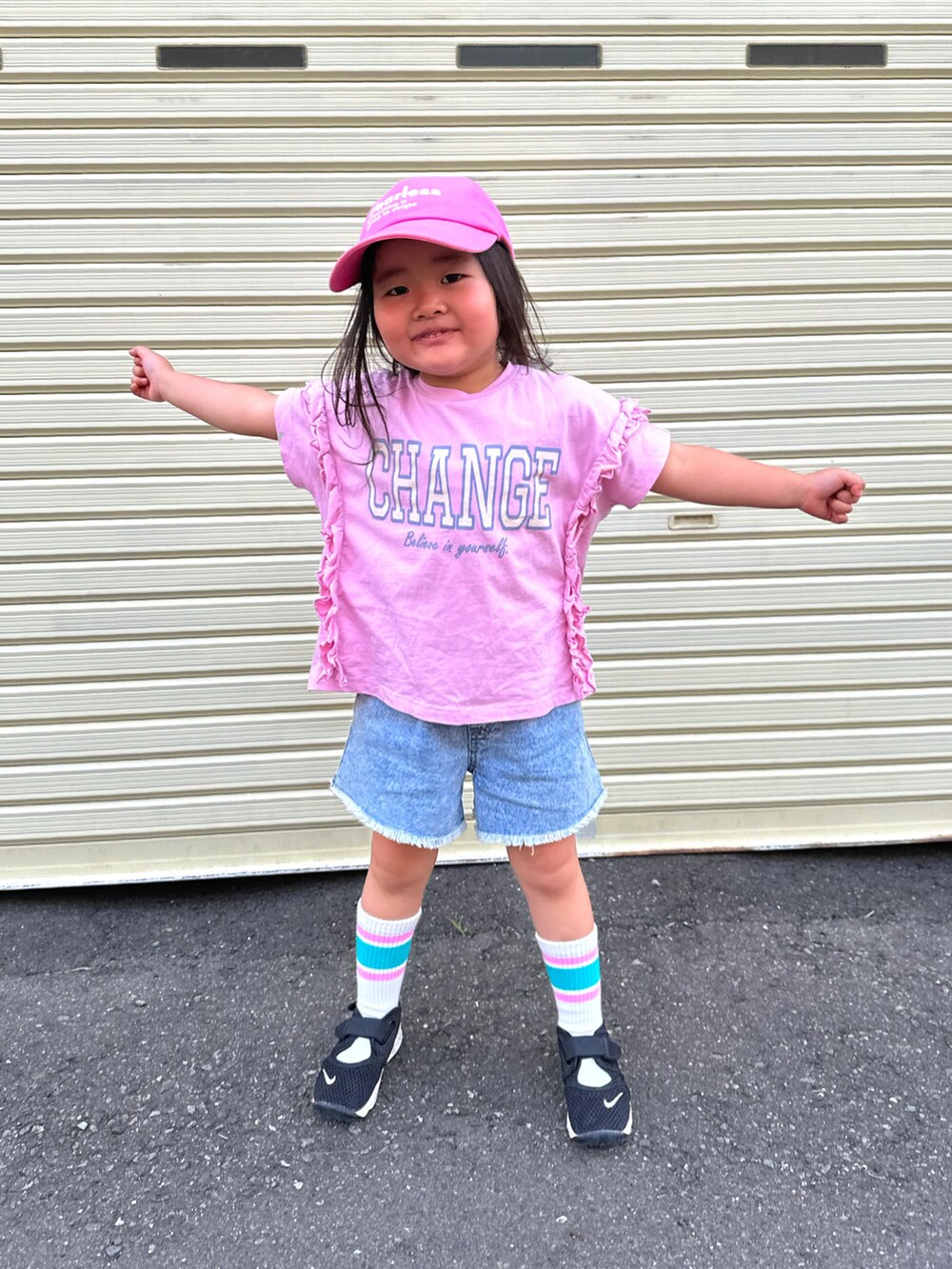 ピンク系のTシャツ/カットソー、ブラック系のスニーカー、ブルー系のデニムパンツを着用したキッズの夏コーディネートの2枚目の写真