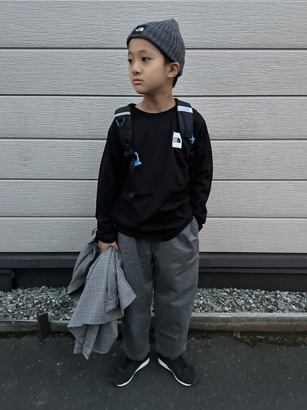 ブラック系のTシャツ/カットソー、ブラック系のバックパック/リュック、グレー系のチノパンツを着用したキッズの秋コーディネートの2枚目の写真