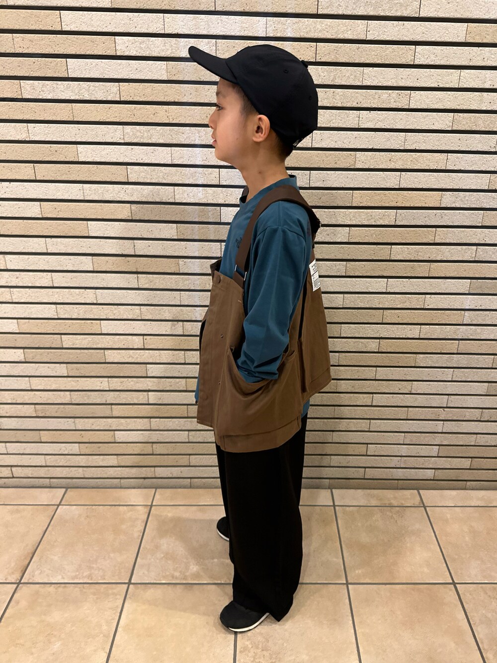 グリーン系のTシャツ/カットソー、ブラウン系のベスト、ブラック系のスラックスを着用したキッズの秋コーディネートの4枚目の写真