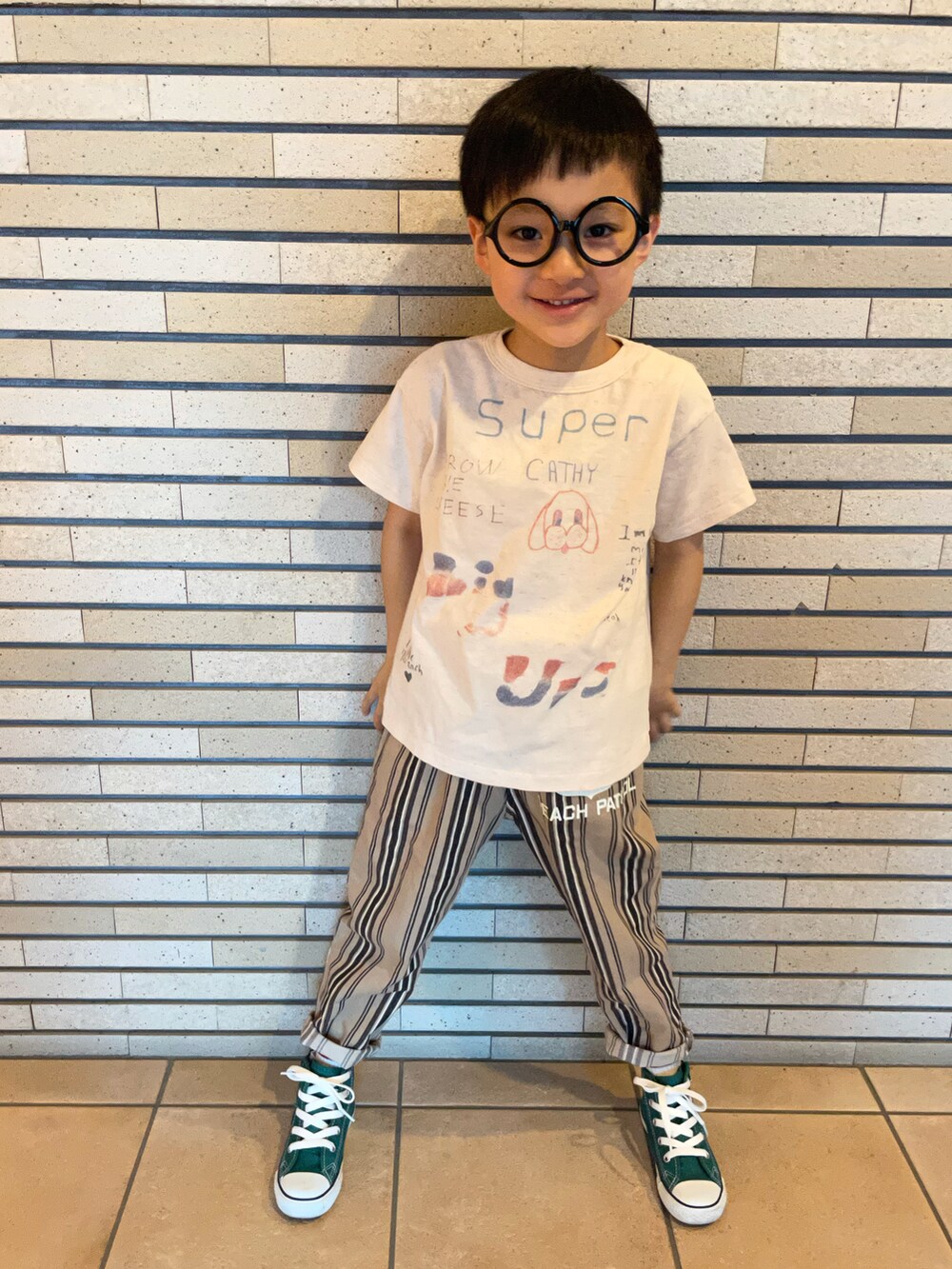 ホワイト系のTシャツ/カットソー、ベージュ系のパンツ、グリーン系のスニーカーを着用したキッズの秋コーディネートの3枚目の写真