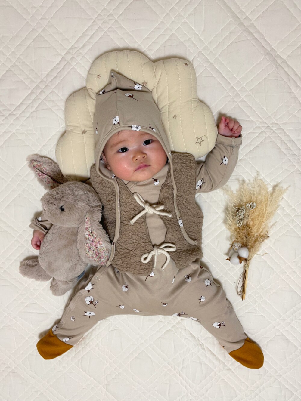 ベージュ系のベスト、ベージュ系のロンパース、ベージュ系のニットキャップ/ビーニーを着用したキッズの秋コーディネートの3枚目の写真