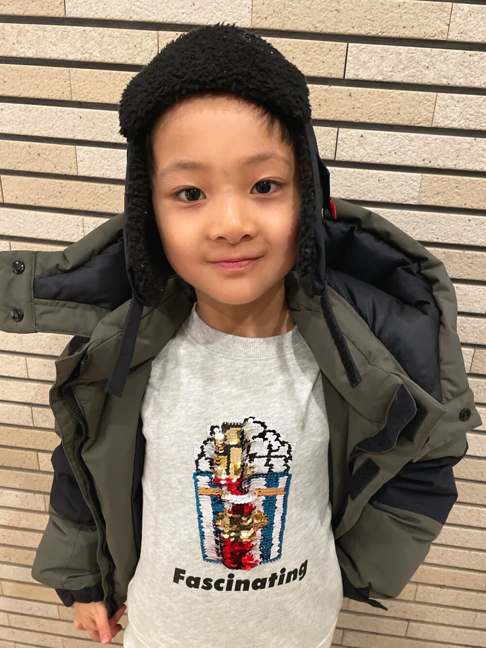 グリーン系のダウンジャケット/コート、ホワイト系のTシャツ/カットソー、ブラック系のブーツを着用したキッズの春コーディネートの4枚目の写真