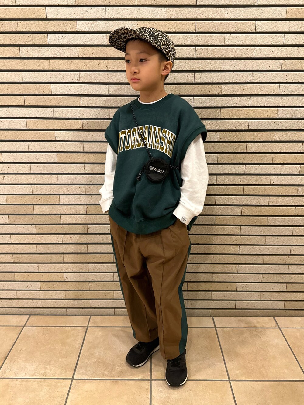 グリーン系のベスト、ホワイト系のTシャツ/カットソー、ブラウン系のパンツを着用したキッズの秋コーディネートの3枚目の写真