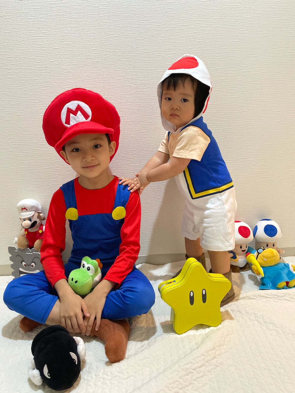 レッド系のオールインワン・サロペット、レッド系のキャスケット、ホワイト系のロンパースを着用したキッズの秋コーディネートの3枚目の写真