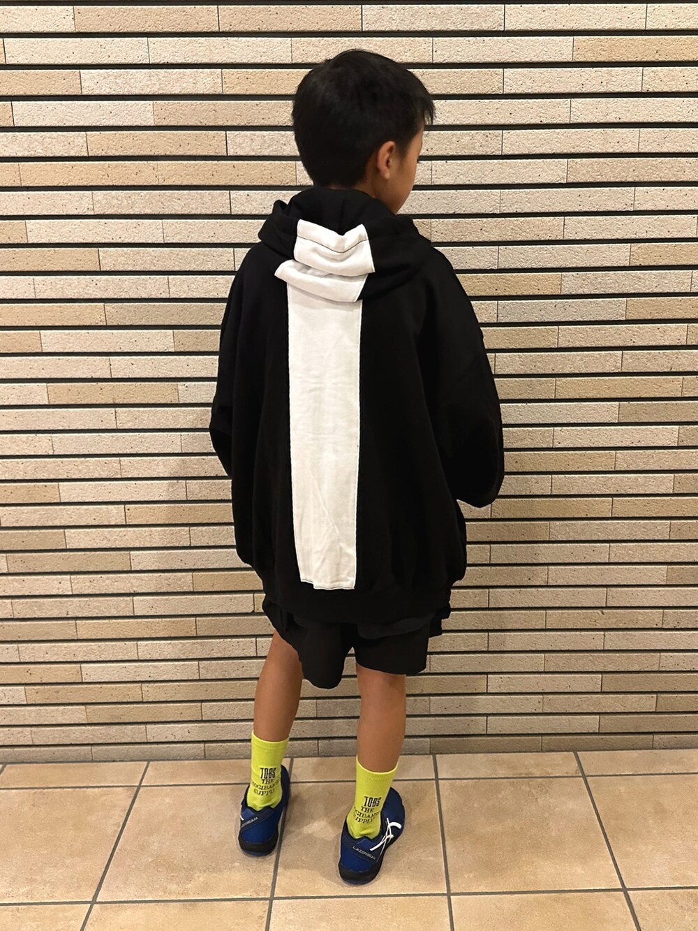 ブラック系のパーカー、ブラック系のパンツ、ブルー系のスニーカーを着用したキッズの秋コーディネートの3枚目の写真