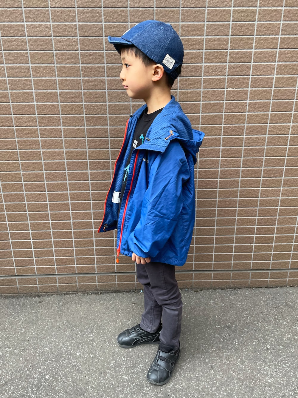 ブルー系のナイロンジャケット、ブラック系のTシャツ/カットソー、ブラック系のスニーカーを着用したキッズの春コーディネートの2枚目の写真