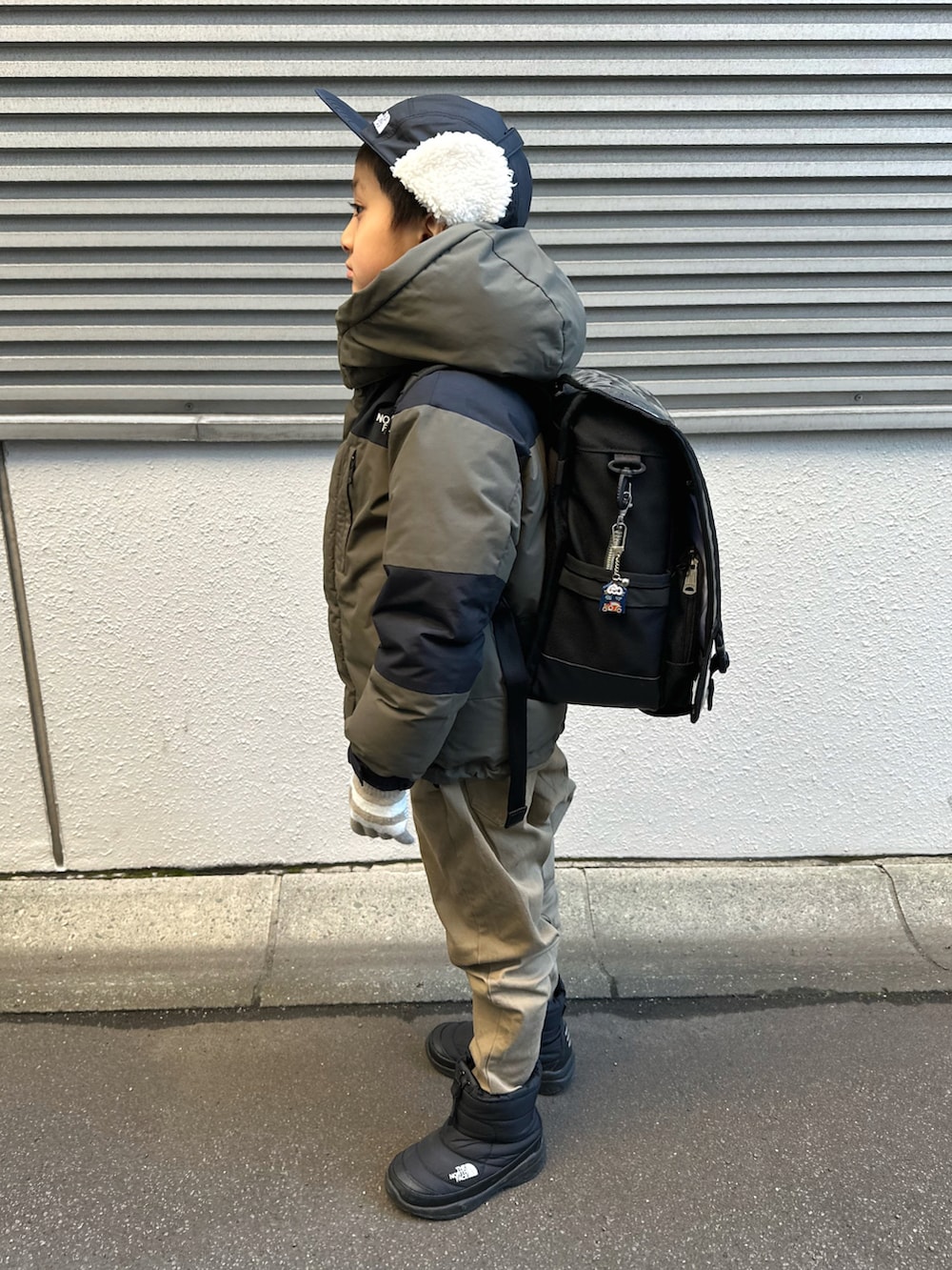 グリーン系のダウンジャケット/コート、ベージュ系のチノパンツ、ブラック系のブーツを着用したキッズの冬コーディネートの2枚目の写真