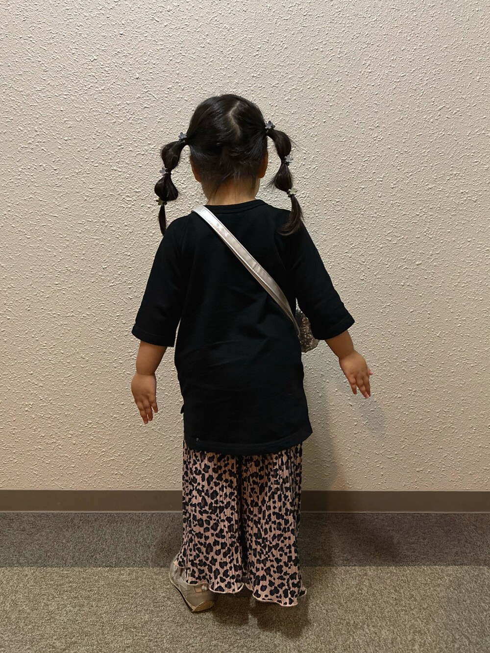 ブラック系のワンピース、ブラウン系のパンツ、シルバー系のショルダーバッグを着用したキッズの秋コーディネートの3枚目の写真