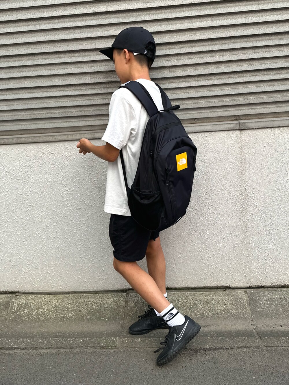 ブラック系のその他パンツ、ブラック系のバックパック/リュック、ホワイト系のTシャツ/カットソーを着用したキッズの夏コーディネートの2枚目の写真