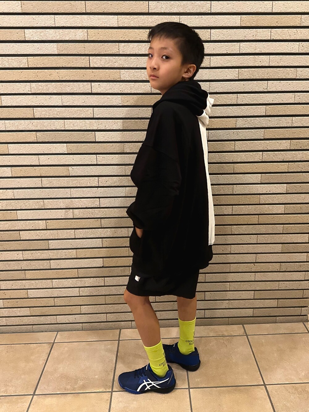 ブラック系のパーカー、ブラック系のパンツ、ブルー系のスニーカーを着用したキッズの秋コーディネートの2枚目の写真