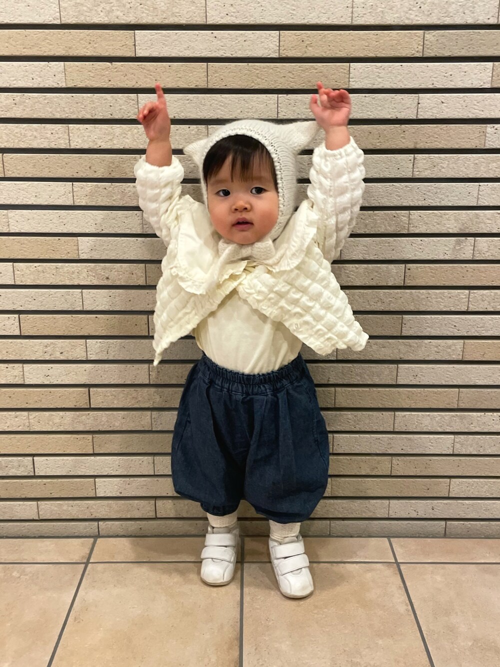 ホワイト系のTシャツ/カットソー、ホワイト系のカーディガン/ボレロ、ブルー系のデニムパンツを着用したキッズの冬コーディネートの2枚目の写真