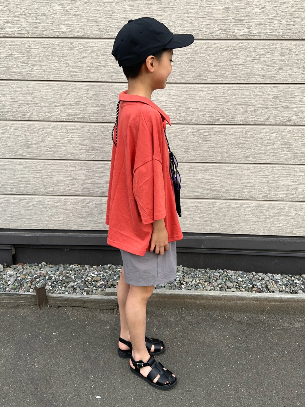 レッド系のセットアップ、ブラック系のサンダル、ブラック系のキャップを着用したキッズの夏コーディネートの4枚目の写真