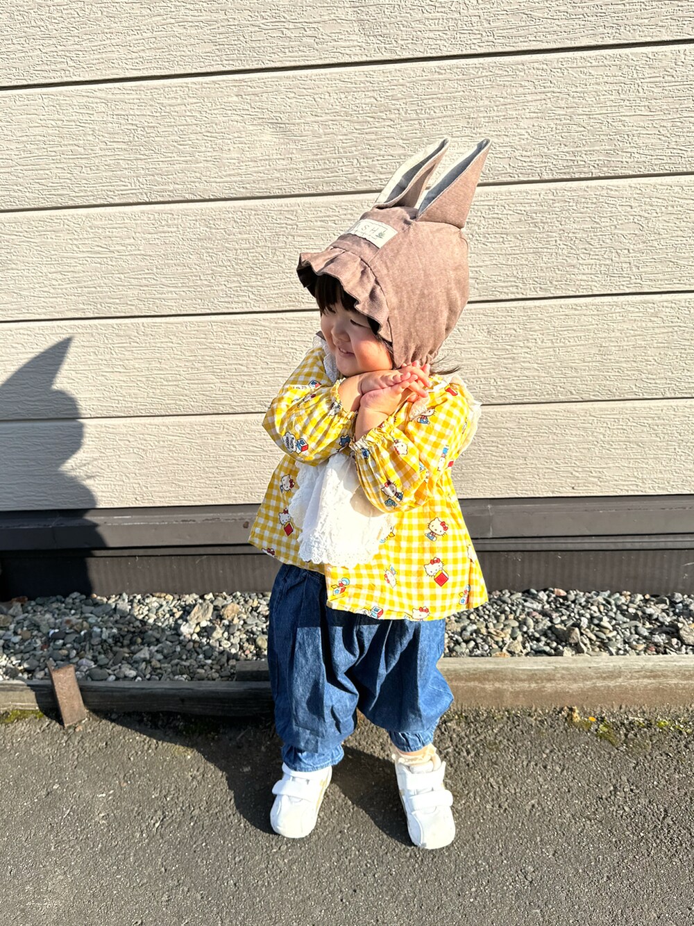 イエロー系のチュニック、ブルー系のデニムパンツ、ホワイト系のスニーカーを着用したキッズの秋コーディネートの2枚目の写真