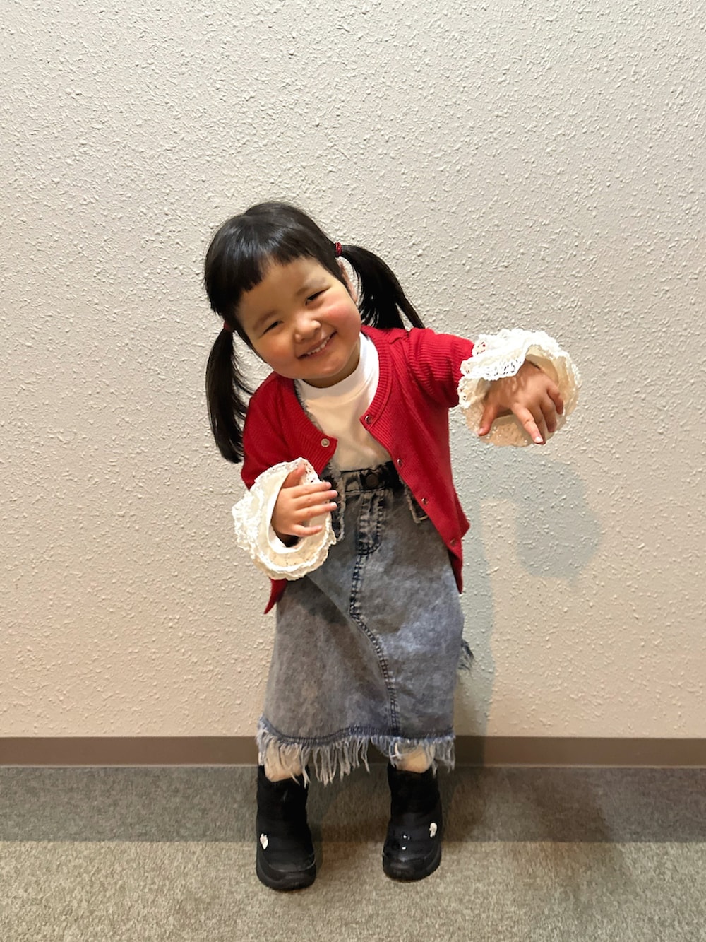 ホワイト系のTシャツ/カットソー、レッド系のカーディガン/ボレロ、ブルー系のスカートを着用したキッズの冬コーディネートの2枚目の写真