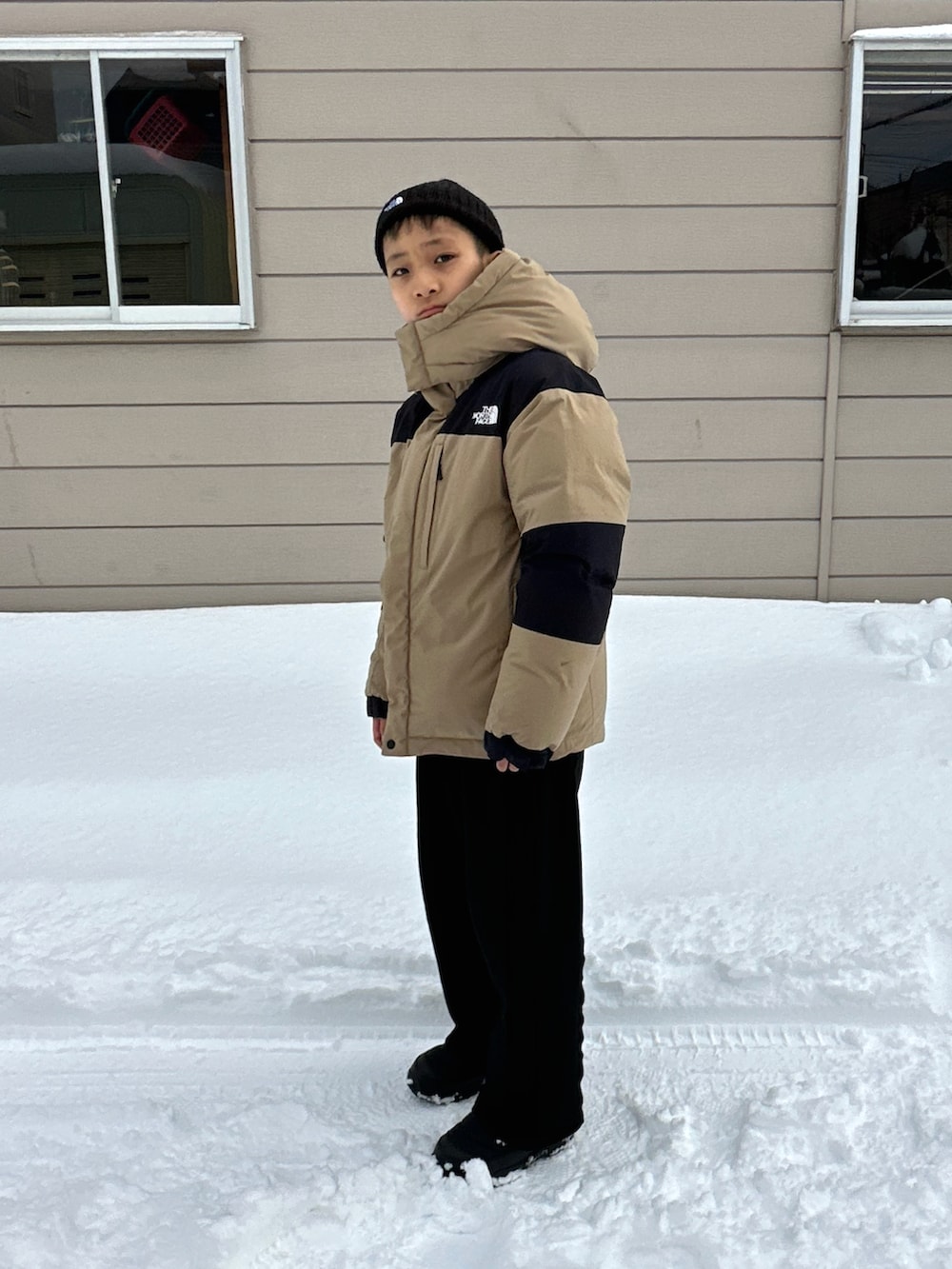 ブラック系のブーツ、ベージュ系のダウンジャケット/コート、ブラック系のスウェットパンツを着用したキッズの春コーディネートの2枚目の写真