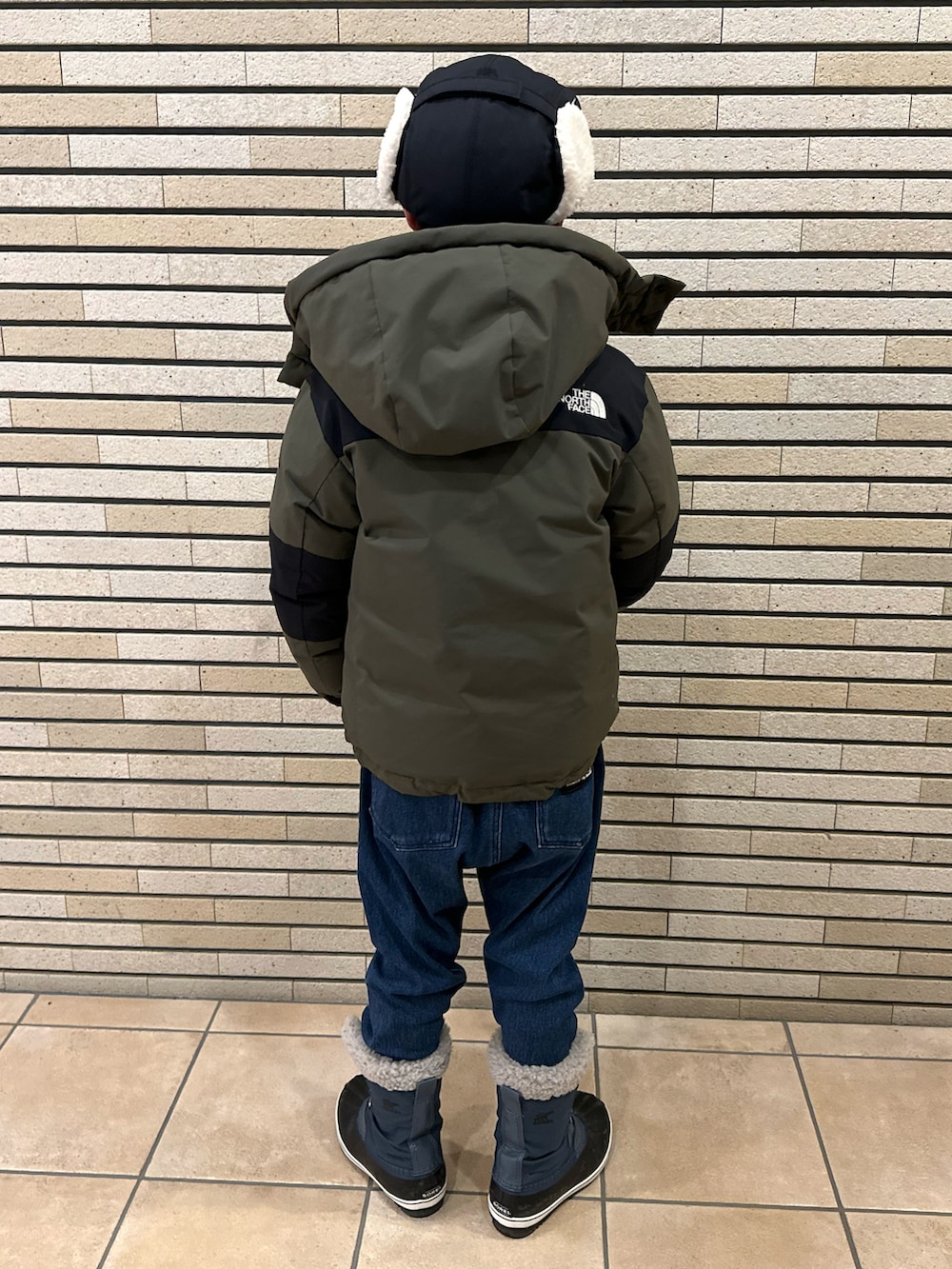 グリーン系のダウンジャケット/コート、ブラウン系のスウェット、ブルー系のデニムパンツを着用したキッズの冬コーディネートの3枚目の写真