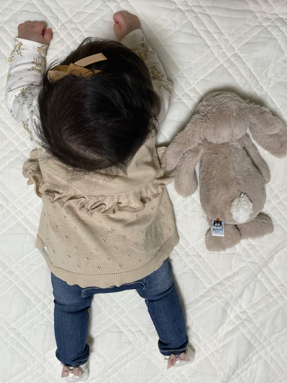 ホワイト系のTシャツ/カットソー、ベージュ系のニット/セーター、ブルー系のデニムパンツを着用したキッズの冬コーディネートの3枚目の写真