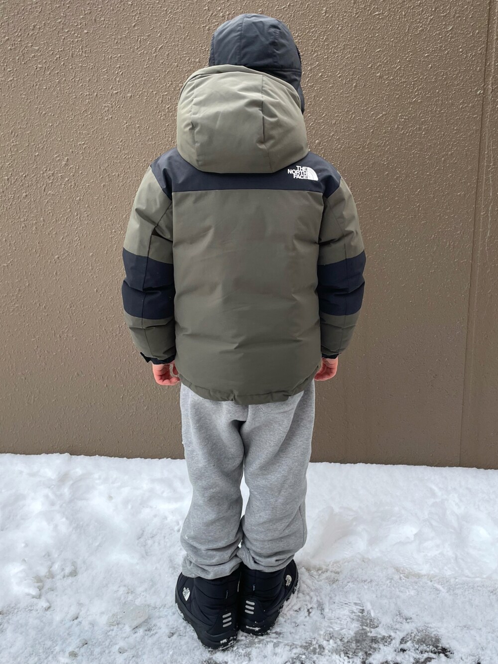 グリーン系のダウンジャケット/コート、グレー系のその他パンツ、ブラック系のブーツを着用したキッズの冬コーディネートの2枚目の写真