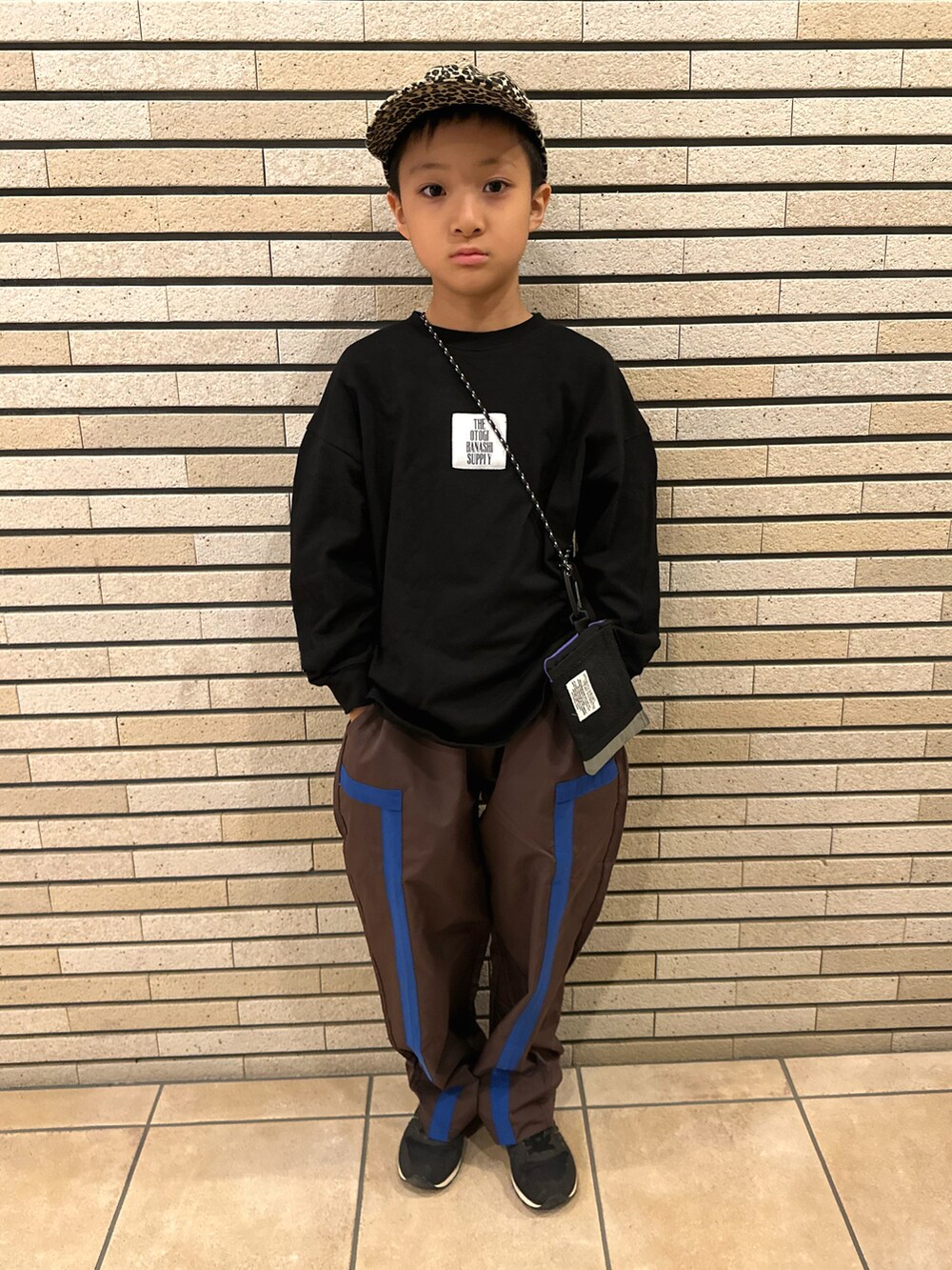 ブラック系のTシャツ/カットソー、ブラウン系のパンツ、ブラック系のスニーカーを着用したキッズの秋コーディネートの2枚目の写真