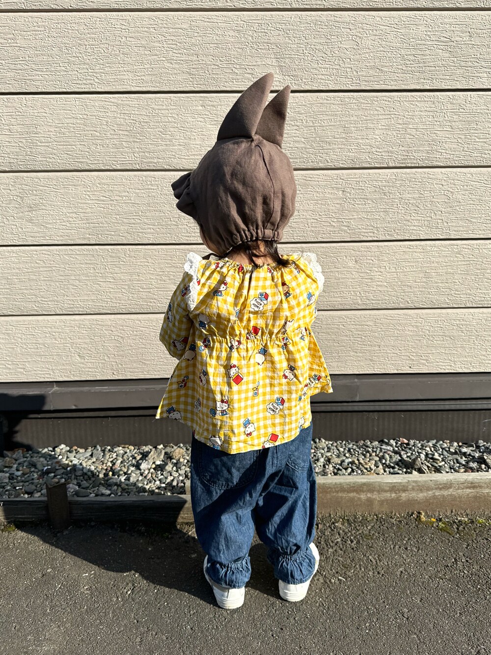 イエロー系のチュニック、ブルー系のデニムパンツ、ホワイト系のスニーカーを着用したキッズの秋コーディネートの3枚目の写真