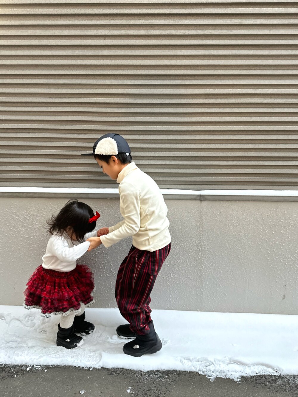 ホワイト系のTシャツ/カットソー、レッド系のその他パンツ、ブラック系のブーツを着用したキッズの冬コーディネートの3枚目の写真