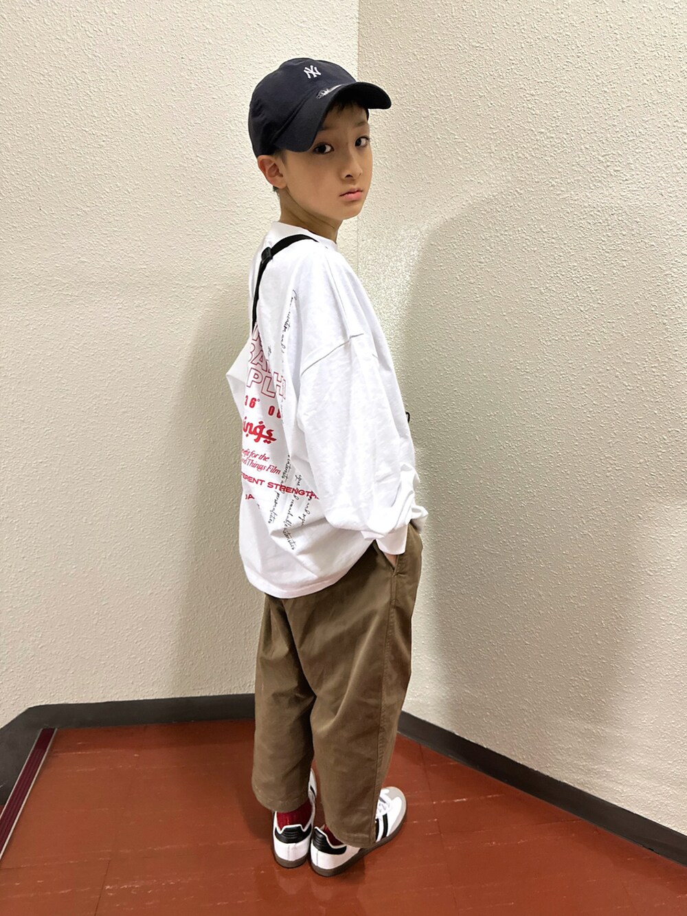 ホワイト系のTシャツ/カットソー、ブラウン系のチノパンツ、ホワイト系のスニーカーを着用したキッズの春コーディネートの3枚目の写真