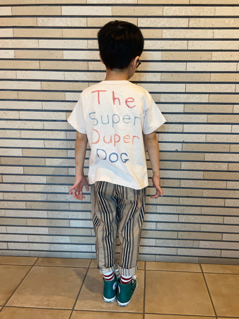 ホワイト系のTシャツ/カットソー、ベージュ系のパンツ、グリーン系のスニーカーを着用したキッズの秋コーディネートの2枚目の写真